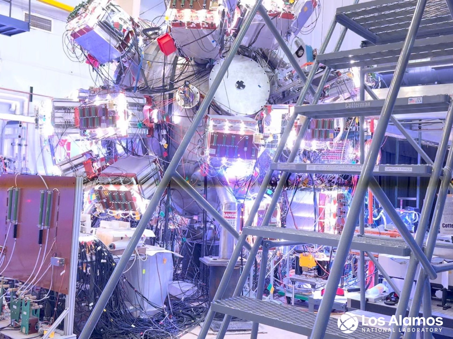Wide view of the PLX vacuum chamber at Los Alamos, a large metal sphere covered in plasma guns and capacitor boxes.