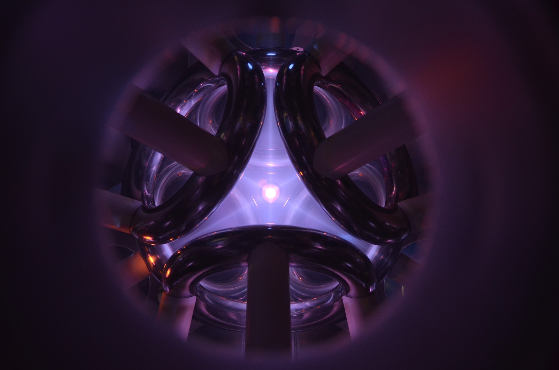 View inside the the Polywell device. The faint pinkish glow of the plasma is visible between inward facing circular magnetic field coils.