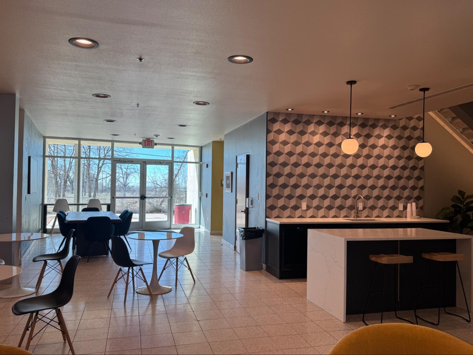 Renovated Innovation Hub common area with a modern kitchenette, cafe seating, and floor-to-ceiling windows